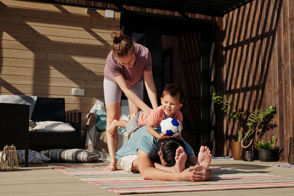 A mom putting a child on the back of a man in a forward fold