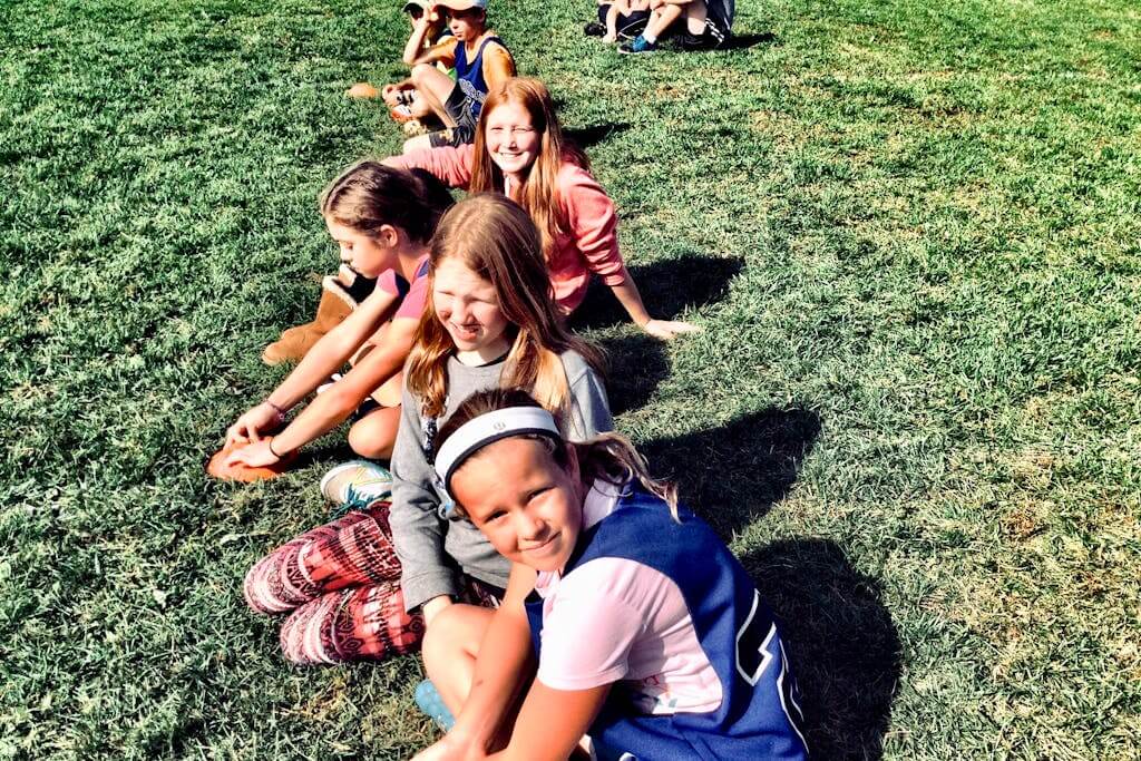 A row of kids sitting on the grass
