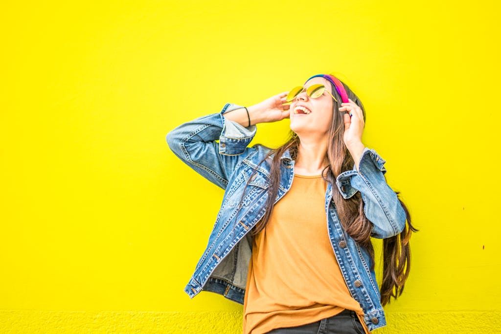A teenager smiling and looking up wearing yellow glasses