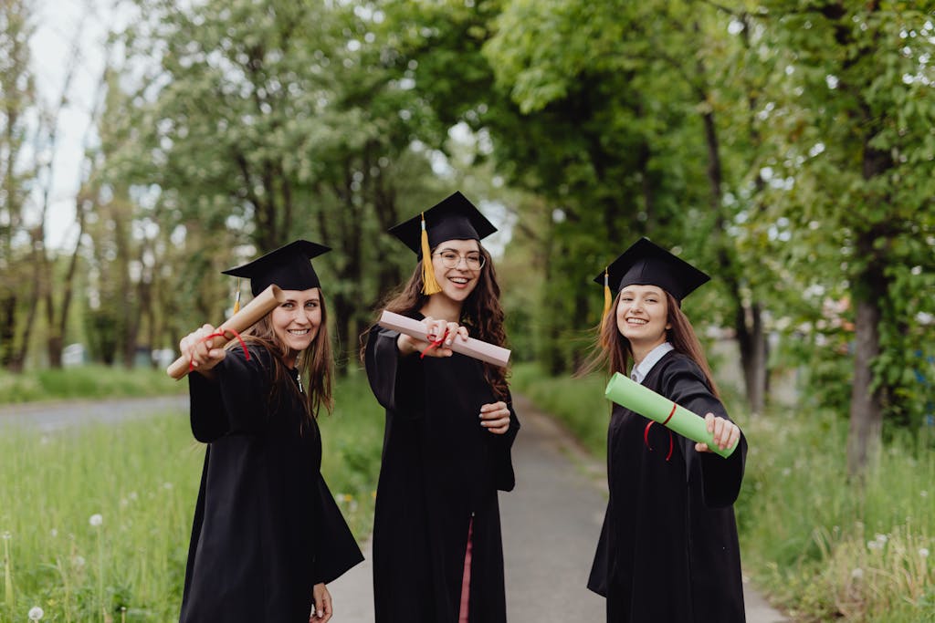 Three girls in graduation gowns and diplomas