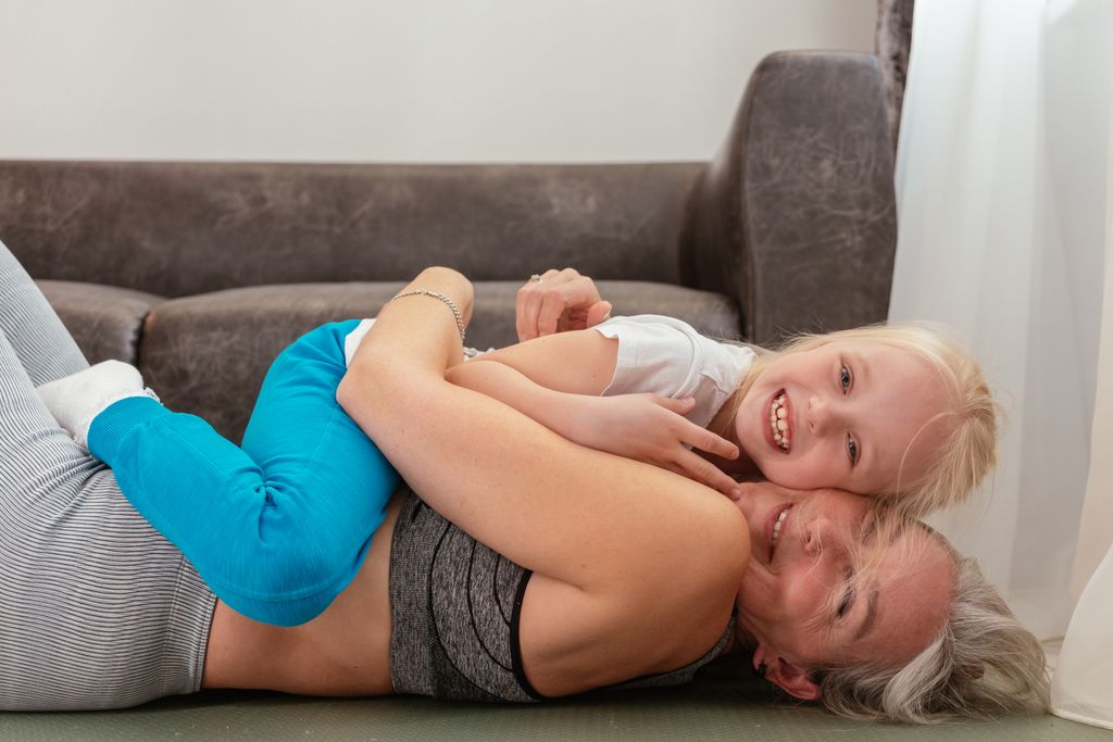 A granddaughter laying on her grandmother in a hug