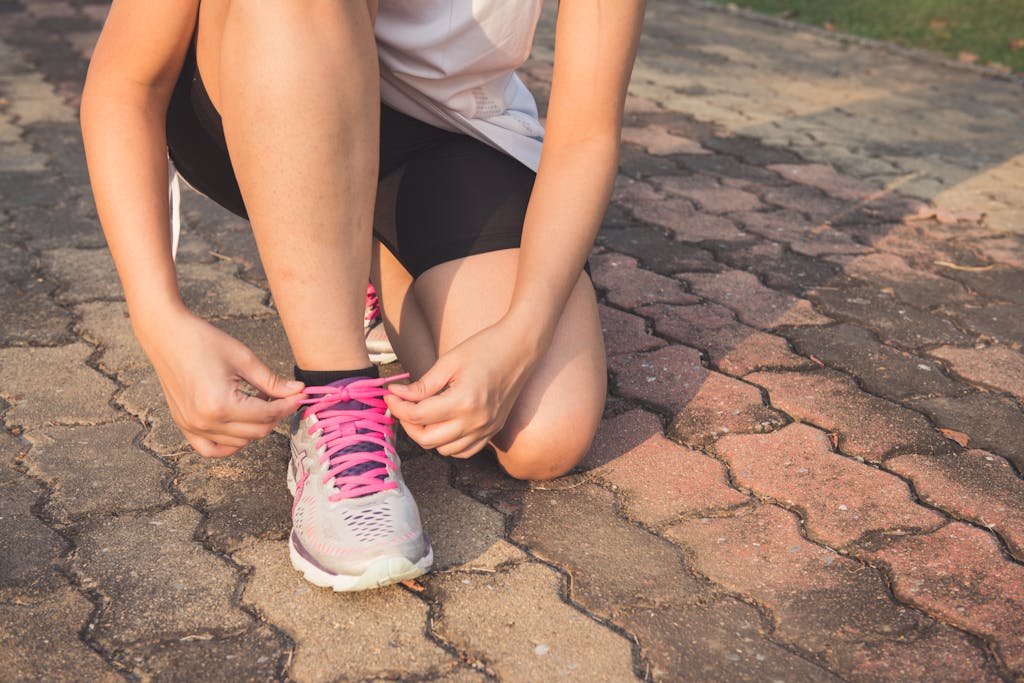 A girl kneeling tying her shoe