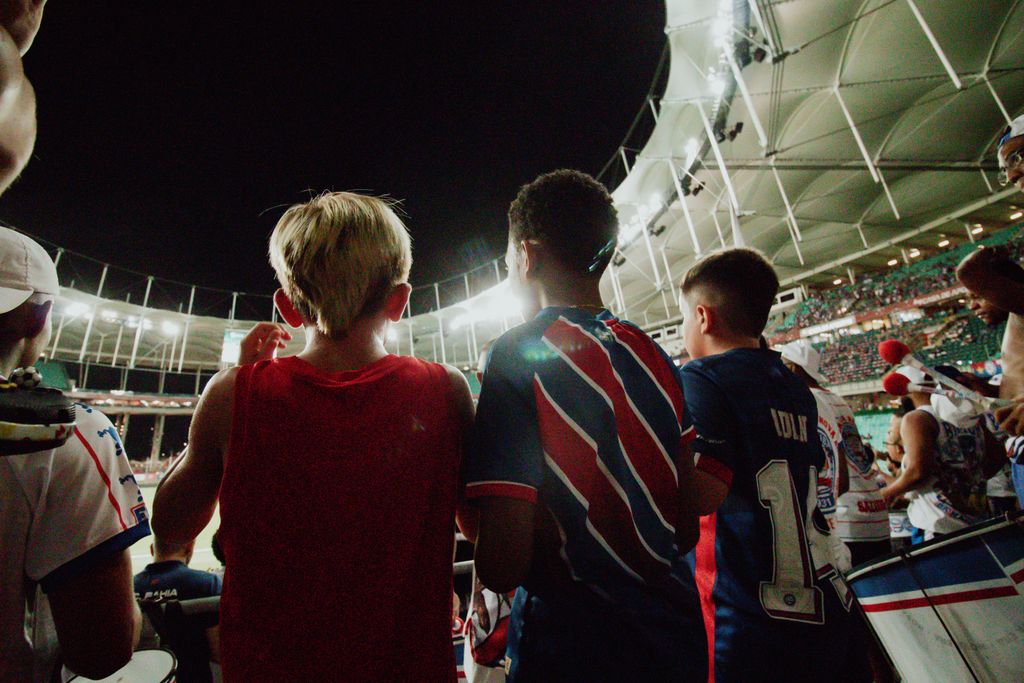 Three boys in a stadium watching soccer