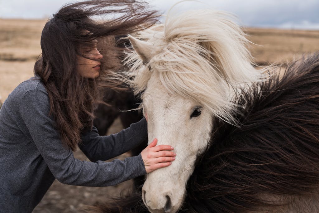 A woman and a horse with hair blowing in the wind