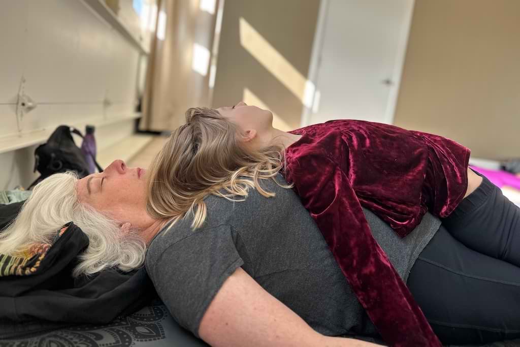 A granddaughter laying on her grandmother in yoga