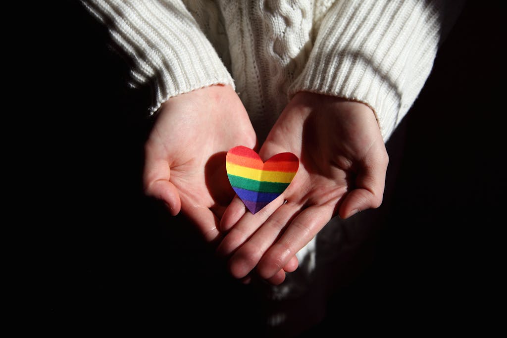Hands holding a rainbow heart
