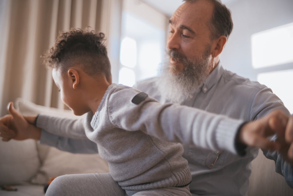 An adult helping a child stretch their arms wide