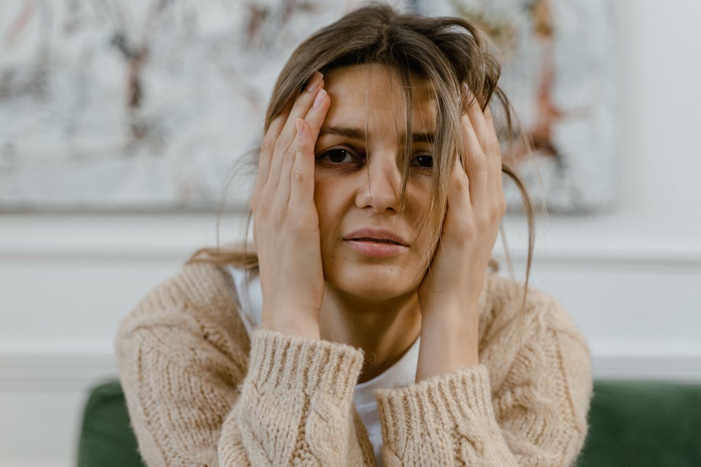 A woman with messy hair and her hands on her head with elbows on the table