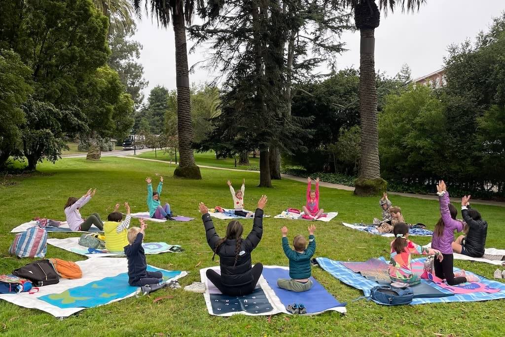 A circle of kids in yoga outdoors