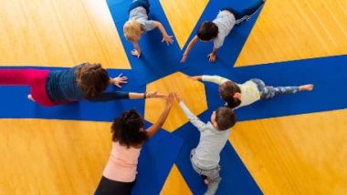 An overhead view of kids doing yoga in a circle 